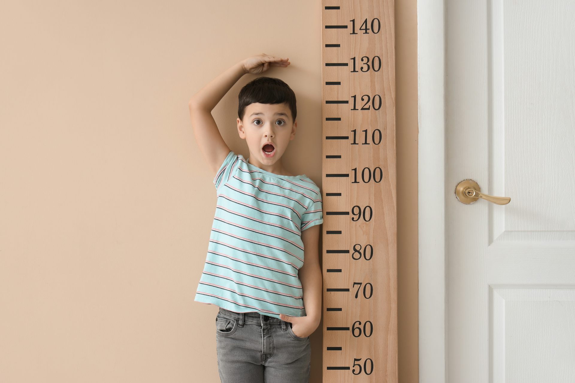 Un niño junto a un metro de medir gigante