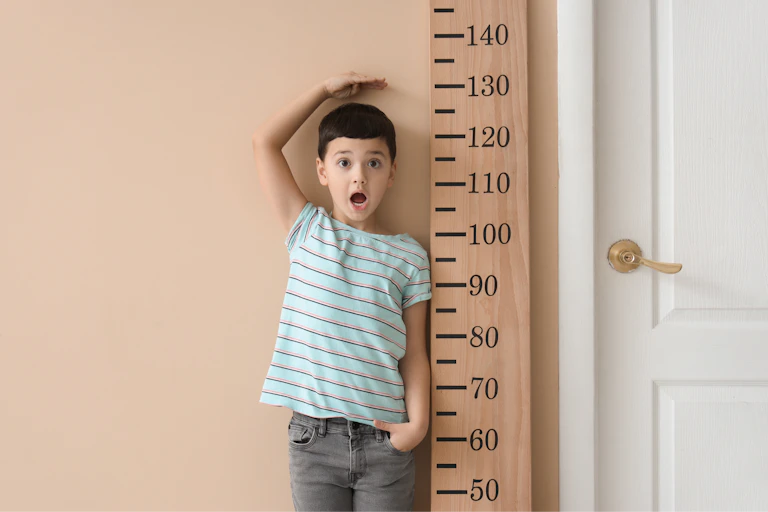 Un niño junto a un metro de medir gigante