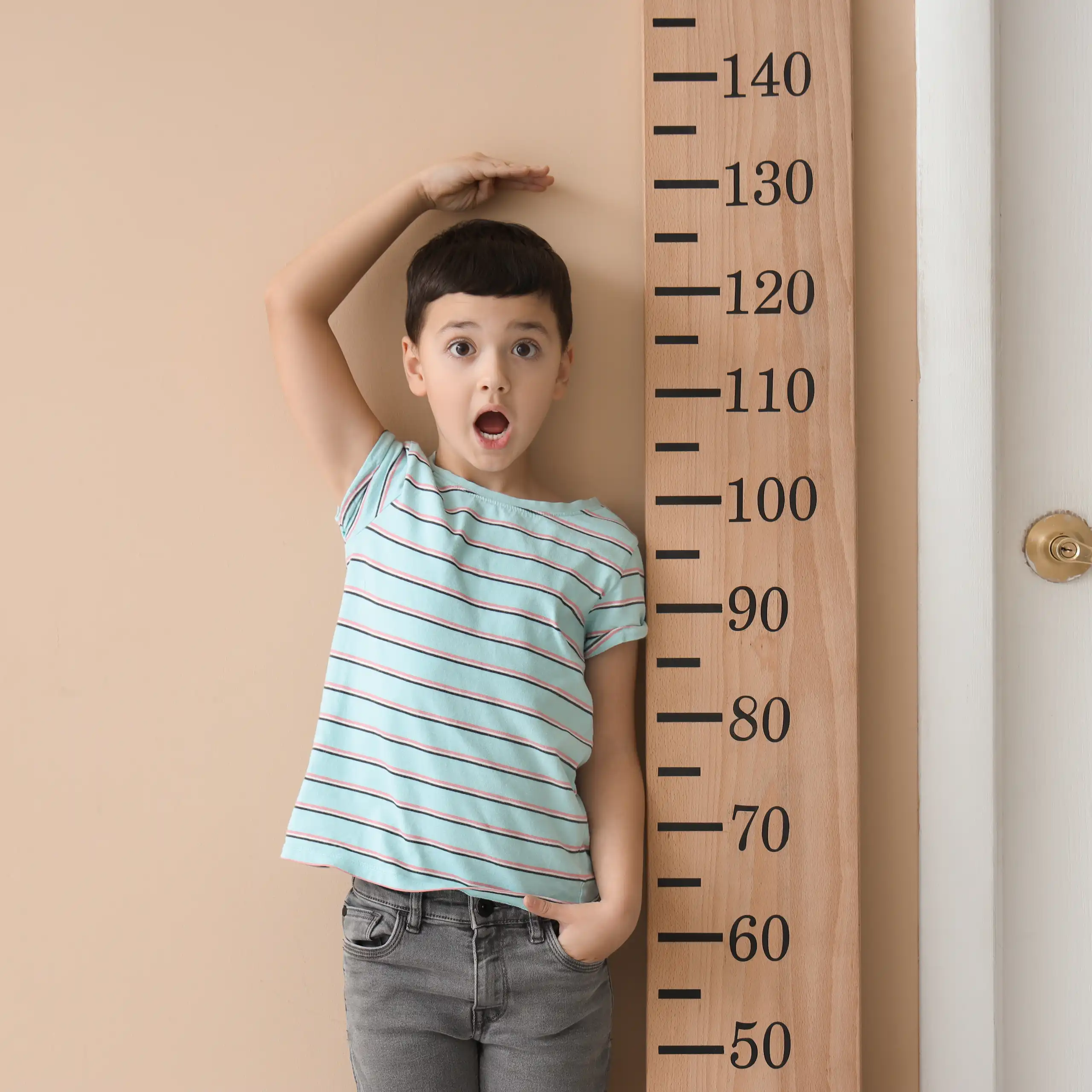Un niño junto a un metro de medir gigante