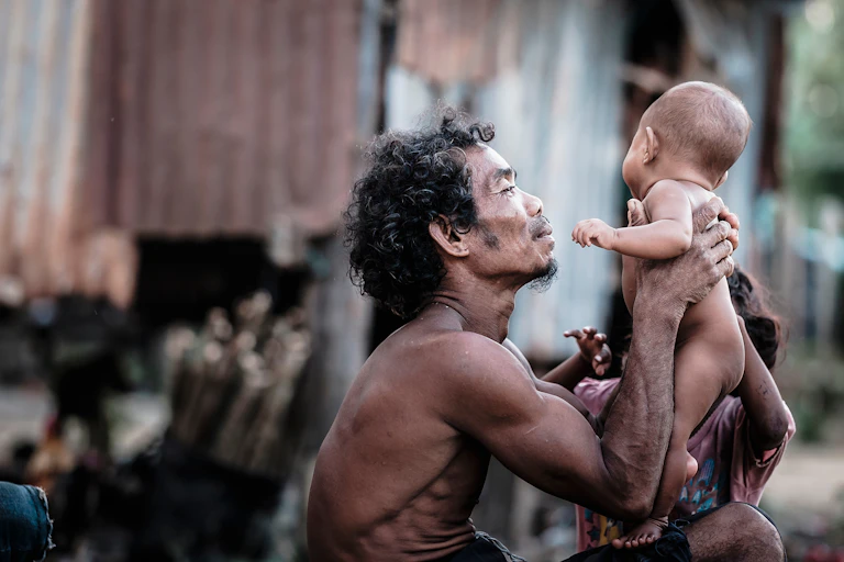 Un homme Orang Asli tenant sonunbébé dans ses bras.