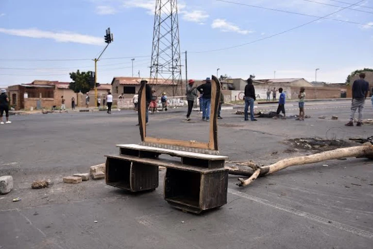People standing on a damaged and blocked road