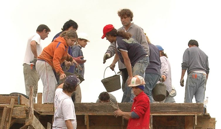 Adults of all ages work together on the construction of a home.
