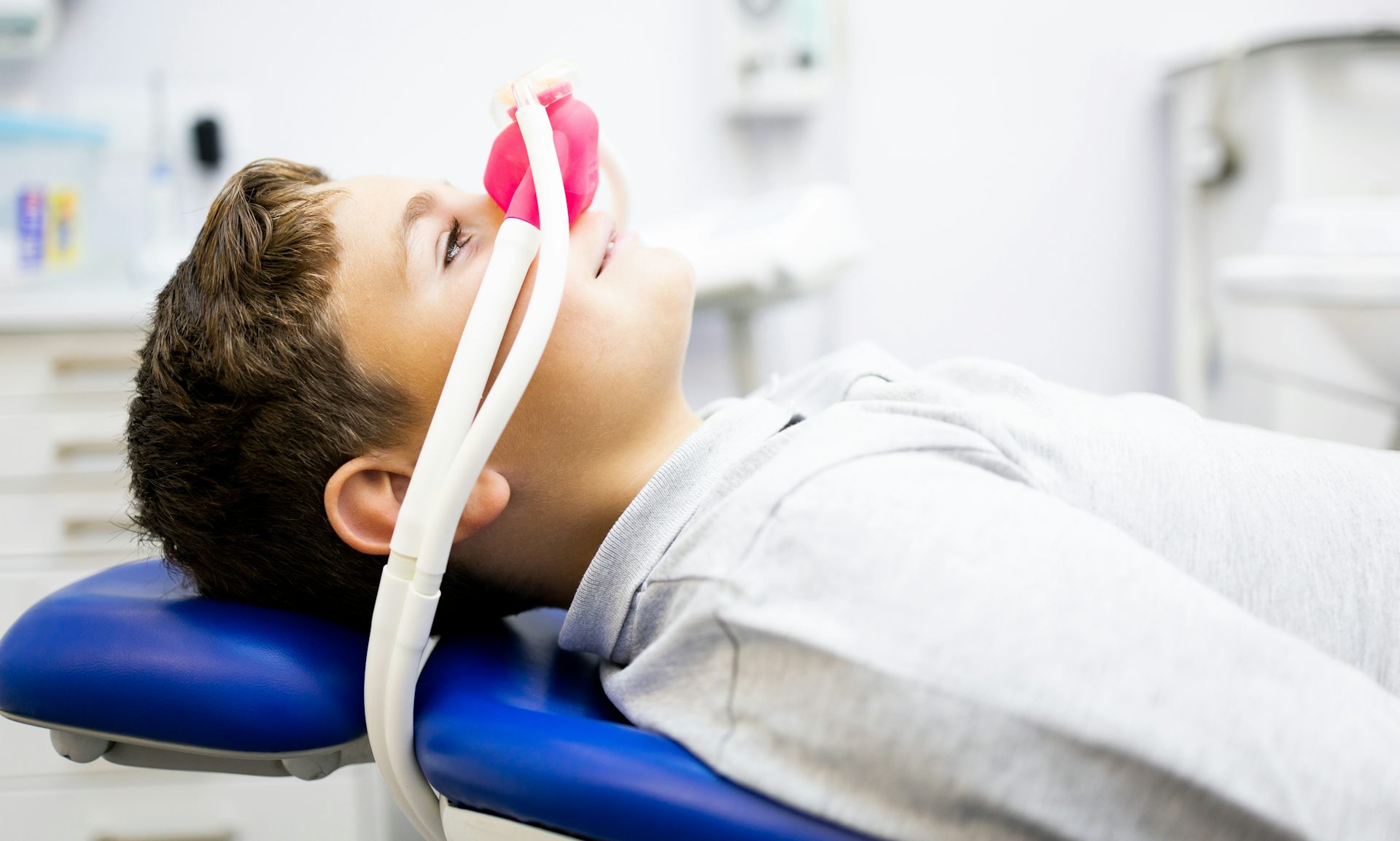 Photo d’un enfant allongé sur un fauteuil d’examen, avec un masque diffusant du MEOPA sur le nez.