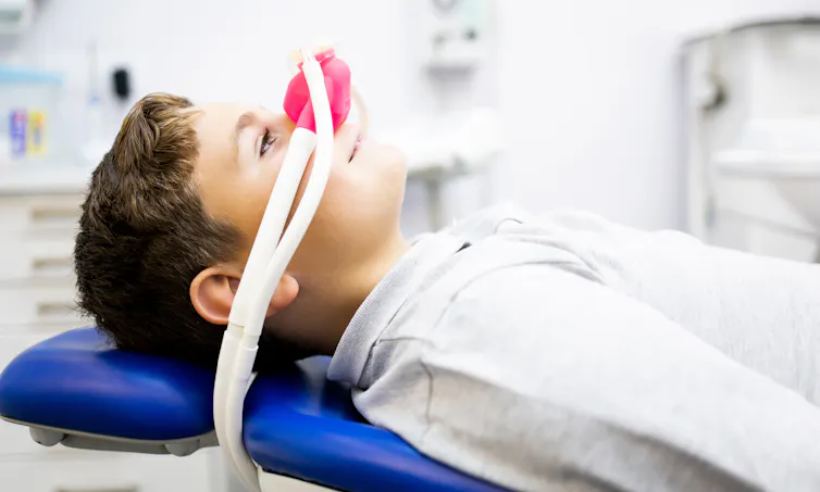 Photo d’un enfant allongé sur un fauteuil d’examen, avec un masque diffusant du MEOPA sur le nez.