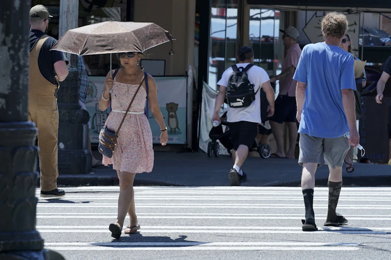 A woman holds an umbrella to ward off the heat.