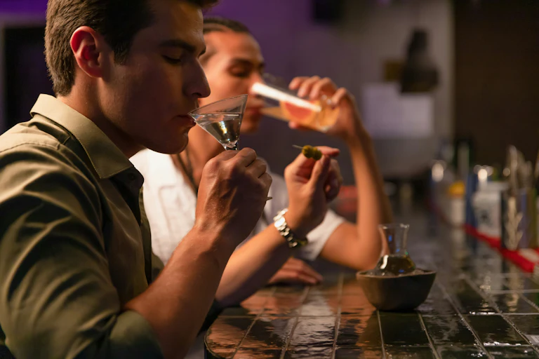 Two people drink alcoholic beverages at a bar
