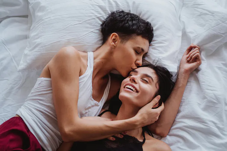 Two women, one with her arms around the other and kissing her forehead