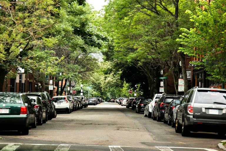 A residential street with brownstones and trees lining both sides of the street.