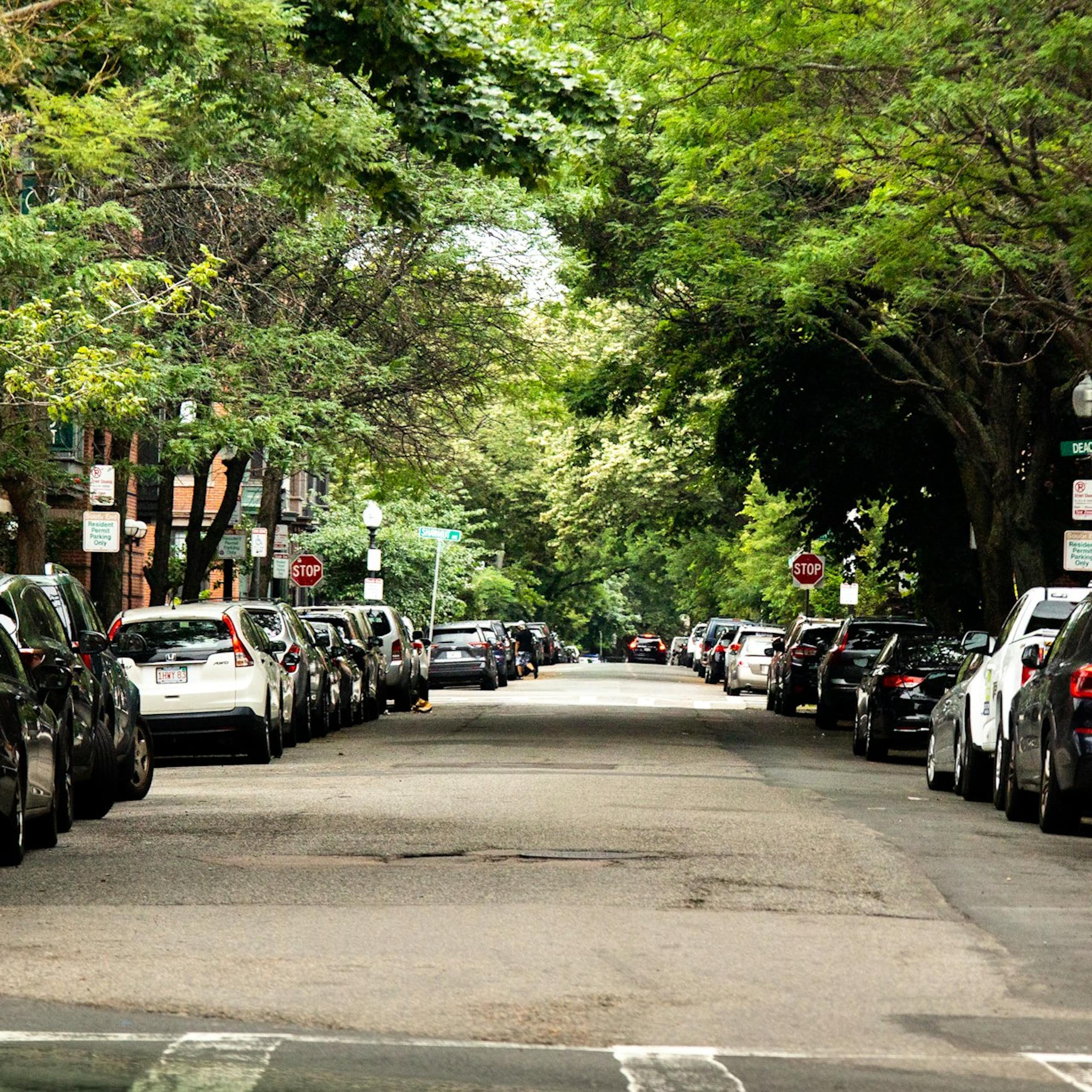 A residential street with brownstones and trees lining both sides of the street.