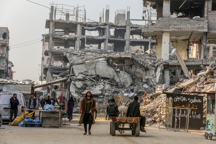 Palestinian people in front of bombed out buildings in Gaza.