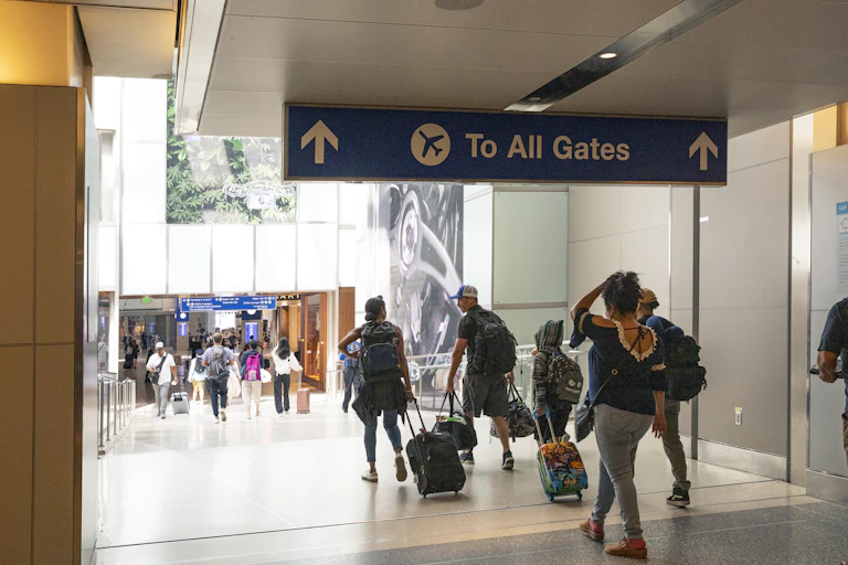 Photo of people at an airport walking towards departure gates.