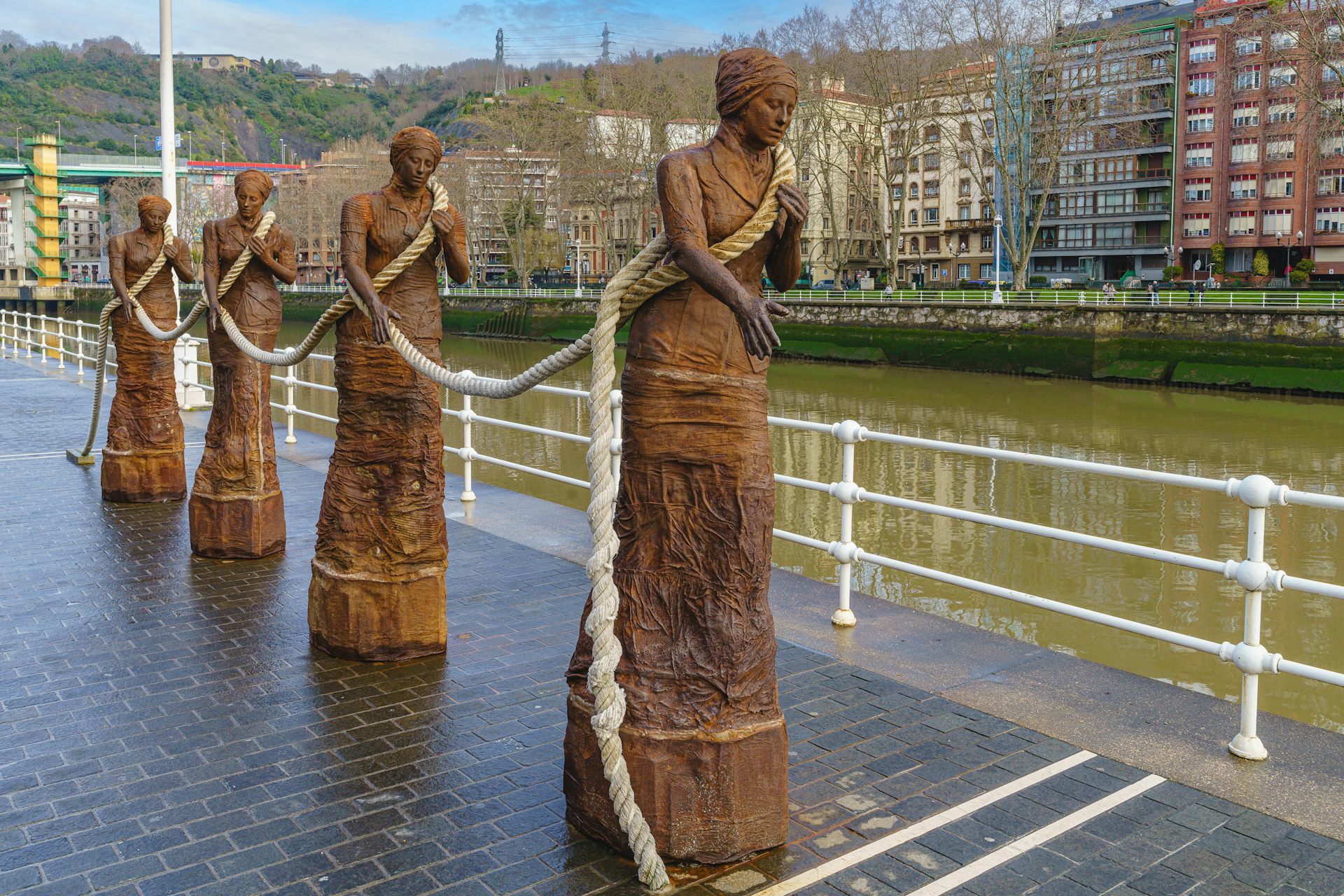 Cuatro esculturas de mujeres enlazadas por una soga