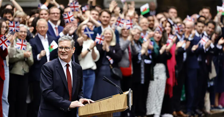 A smiling Keir Starmer delivers his victory speech, with a crowd of supporters behind him
