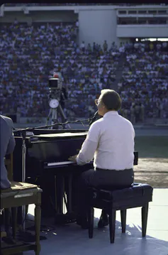 A man playing the piano in front of a huge crowd.