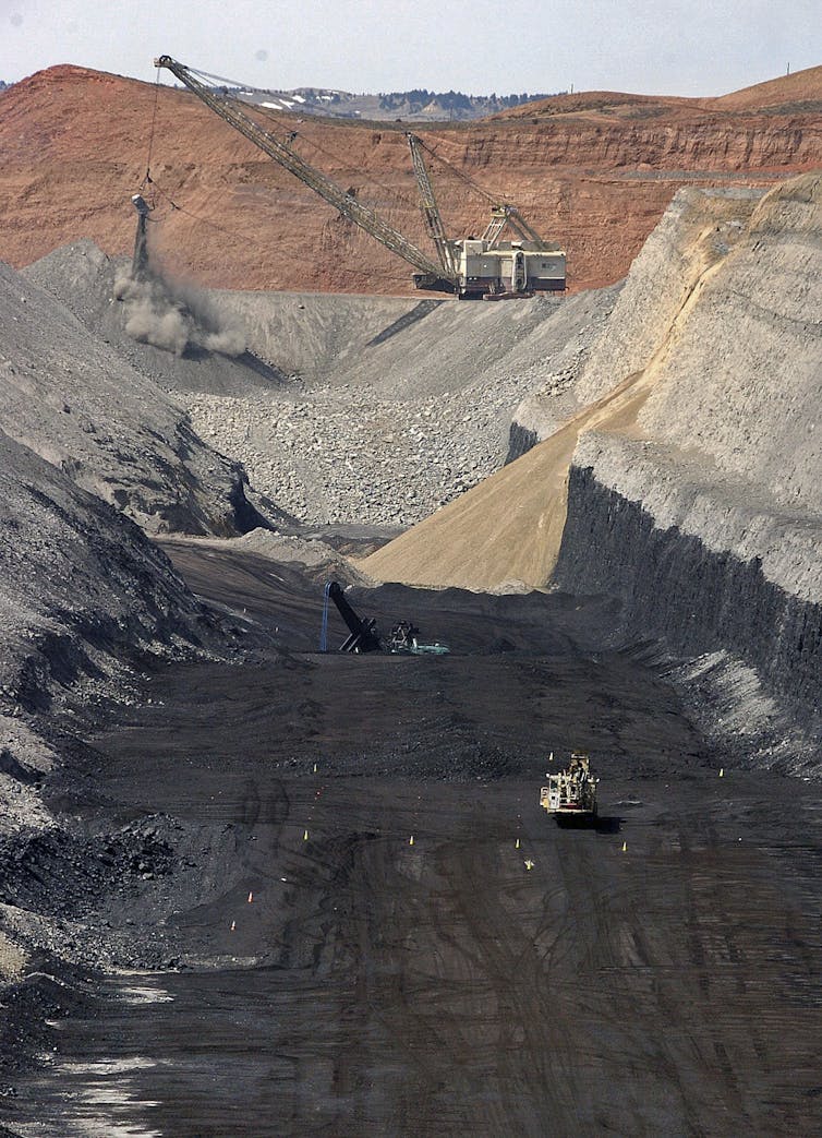 A large piece of mechanical equipment picks up coal from the ground.