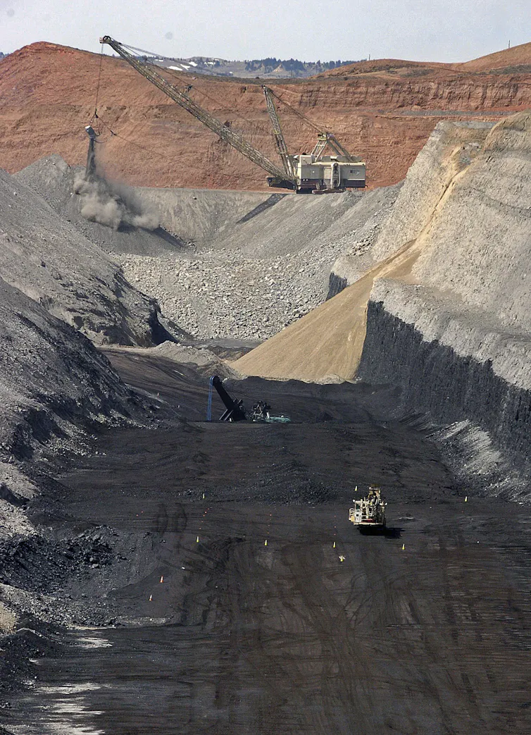 A large piece of mechanical equipment picks up coal from the ground.