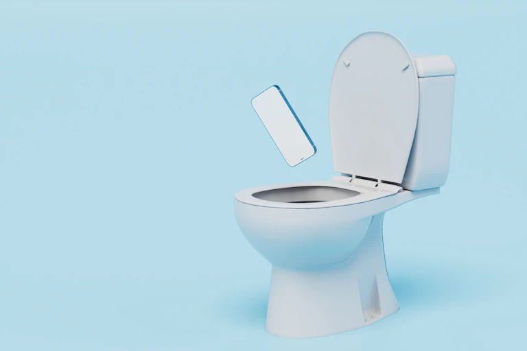 A smartphone falls into an open toilet seat.