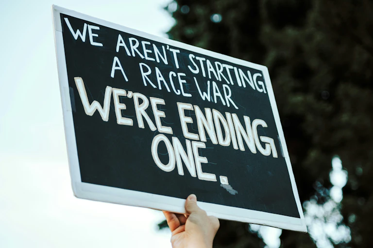 A protester holds a sign that reads 'we aren't starting a race war, we're ending one.'
