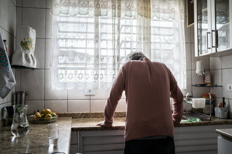 Older man leaning forward over his kitchen sink, suggesting he is not feeling well.