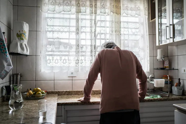 Older man leaning forward over his kitchen sink, suggesting he is not feeling well.