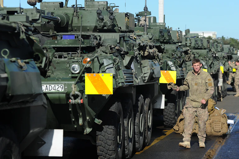 Soldier stands next to a line of military vehicles