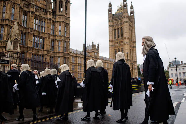 A procession of judges walking across the street towards Parliament