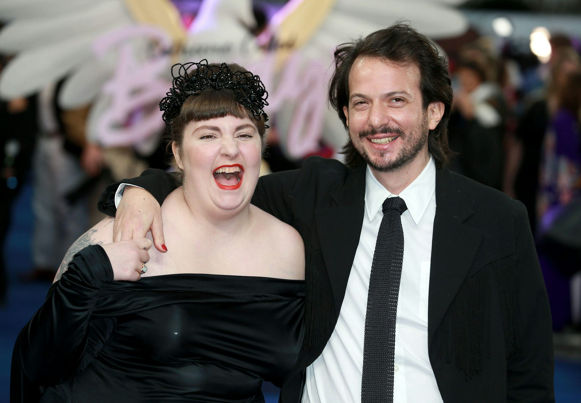 A young couple dressed up in black for a night out looking happy together.