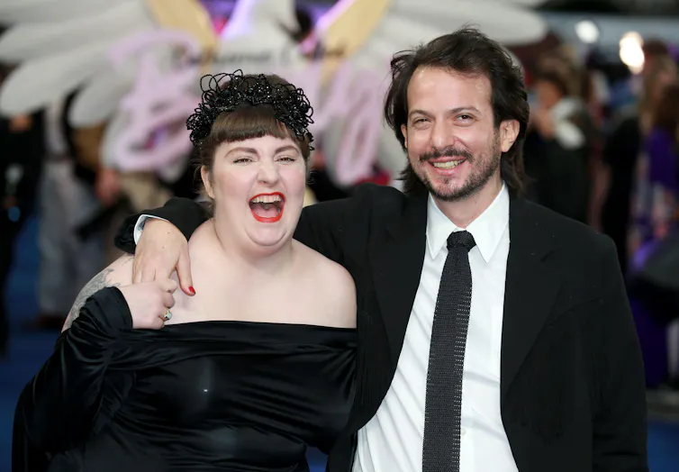 A young couple dressed up in black for a night out looking happy together.