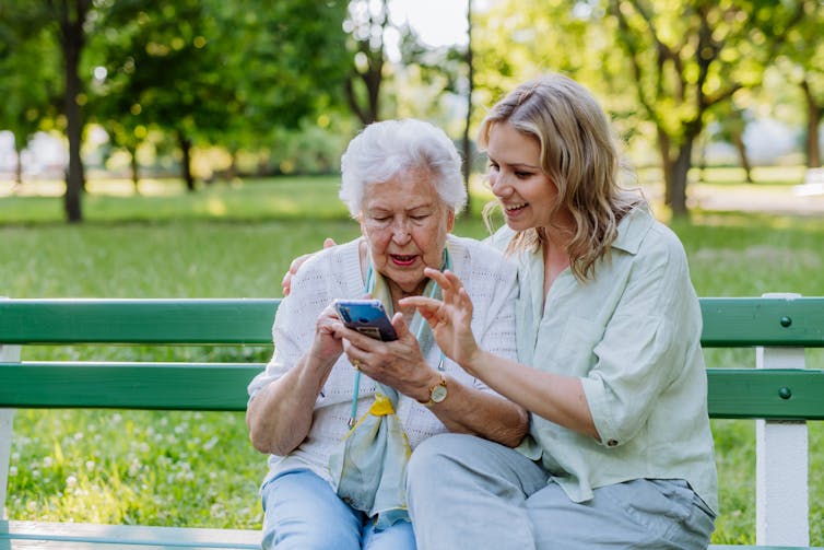 Two women from different races use a smartphone simultaneously.