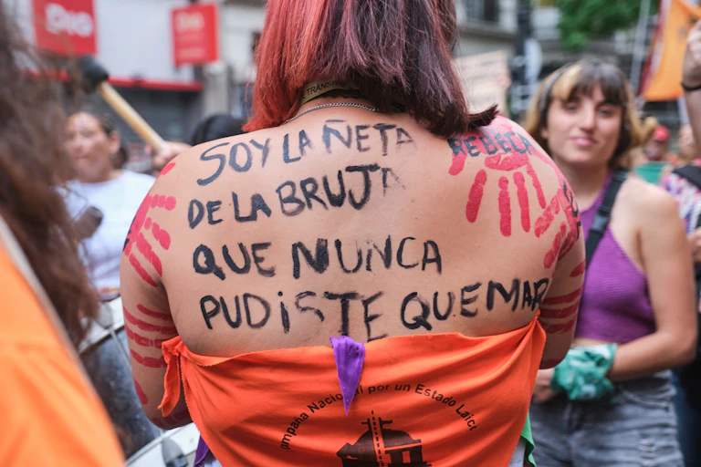 Mujer con una escritura feminista en la espalda: Soy la nieta de la bruja que nunca podrías quemar.
