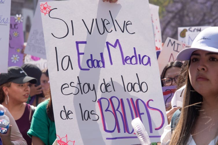 Una mujer sostiene un cartel que dice Si vuelve la edad media estoy del lado de las brujas