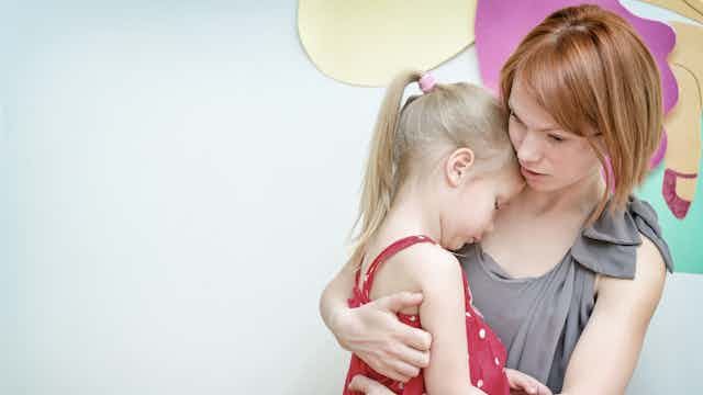 Woman hugging sad looking little girl
