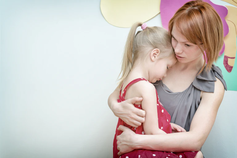Woman hugging sad looking little girl