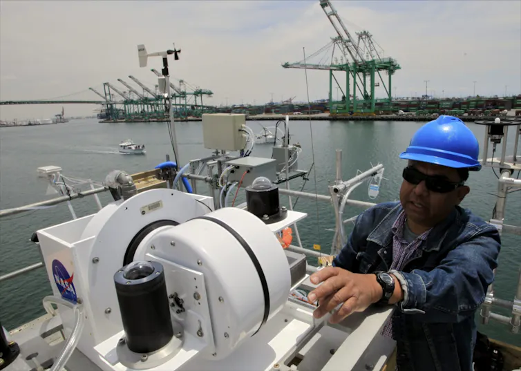 A person seen atop a ship with equipment.