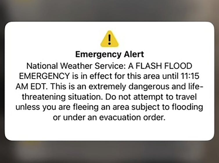 Why it can be hard to warn people about dangers like floods – communication researchers explain the role of human behavior a small yellow triangle enclosing a black exclamation point sits above a block of text