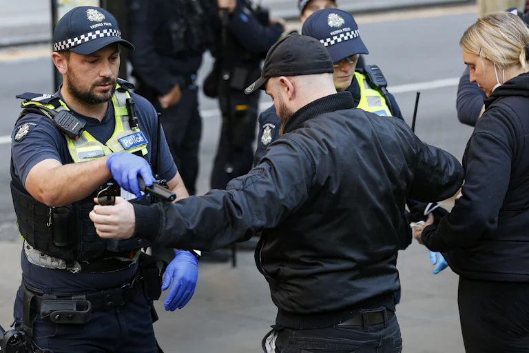 Police officers conduct searches during a rally in Melbourne in 2025.