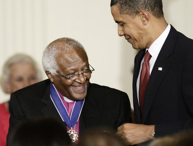 Bishop Desmond Tutu standing next to and laughing with President Barack Obama