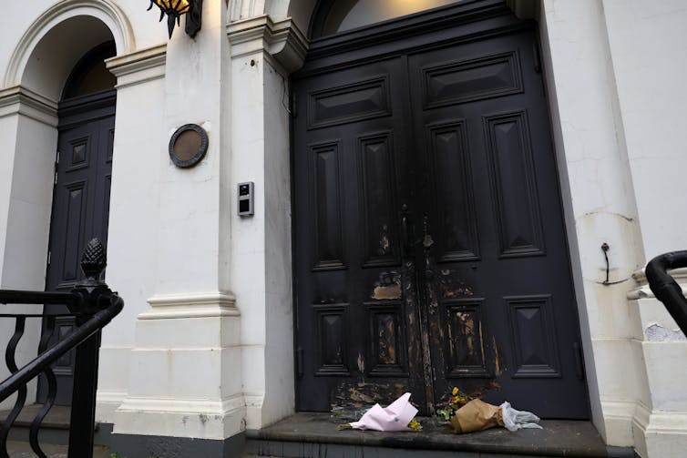 Two bunches of flowers sit outside a fire damaged door