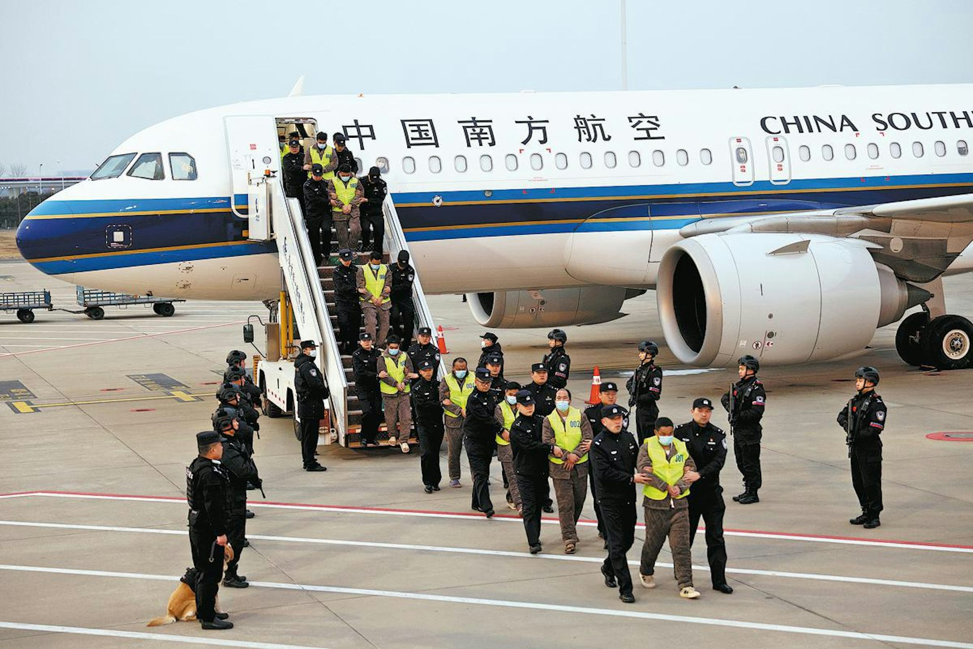 Chinese citizens suspected of committing telecoms fraud are escorted off a plane by police officers.
