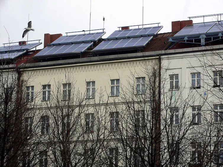 An apartment building with panels mounted on the roof.