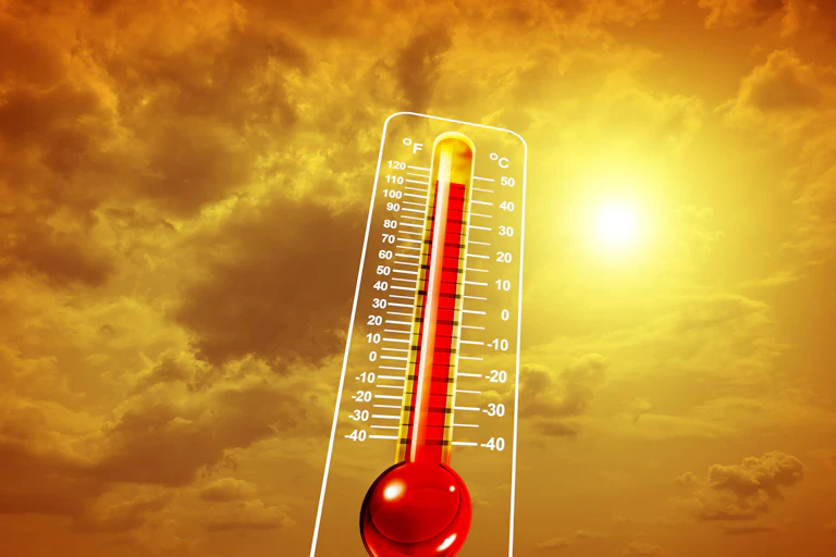 Un termómetro marcando una temperatura alta y un cielo nublado con el sol de fondo