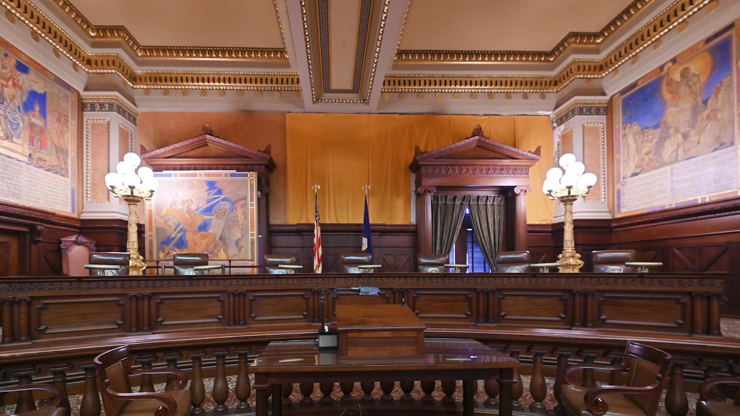 Interior of stately courtroom with dark wood furnishings and gold trim