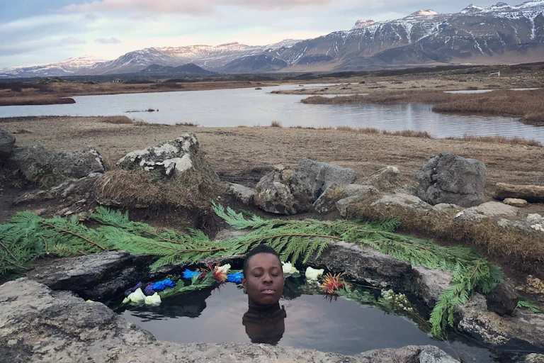 Photograph of a man in a small rock pool by the ocean