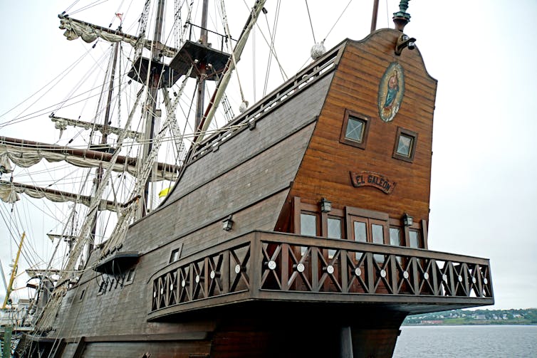 The rear of a large wooden sail boat with more than one deck.