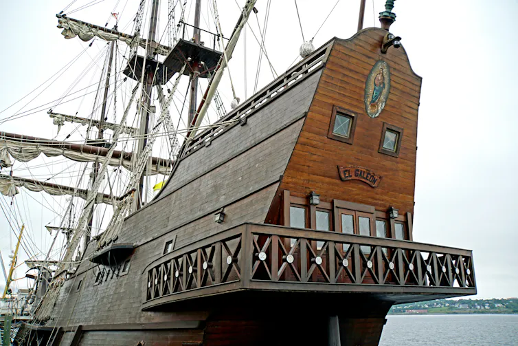The rear of a large wooden sail boat with more than one deck.
