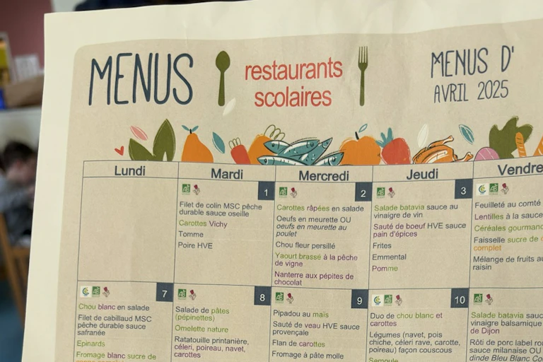 A school food calendar menu with illustrations of vegetables, a fork and knife.