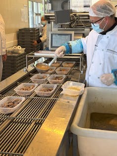 Almuerzos escolares, en modo francés: no se trata solo de nutrición, sino también juntos y 'Bon apetito' 3 El cocinero vio que las comidas se colocan en los platos.