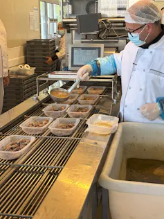 A cook seen putting meals into dishes.