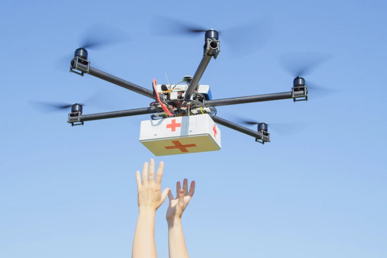 Drone delivering health care in white box with Red Cross logo, hands outstretched to catch drone delivery