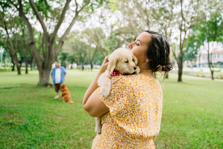 A woman carries her dog in a park.